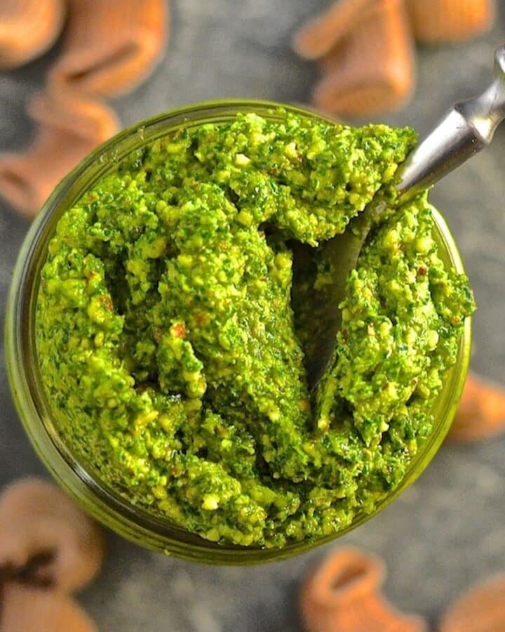 a jar of kale almond pesto with a spoon in it. Photo taken from above.