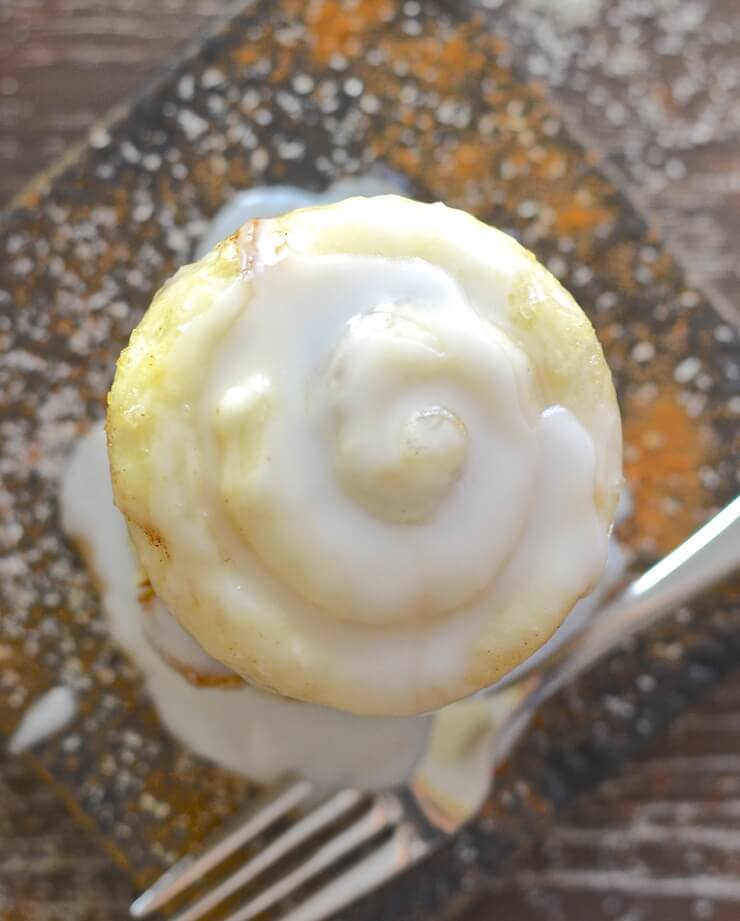 cinnamon roll in a mug turned out on a square plate and frosted. Shot taken from above. 