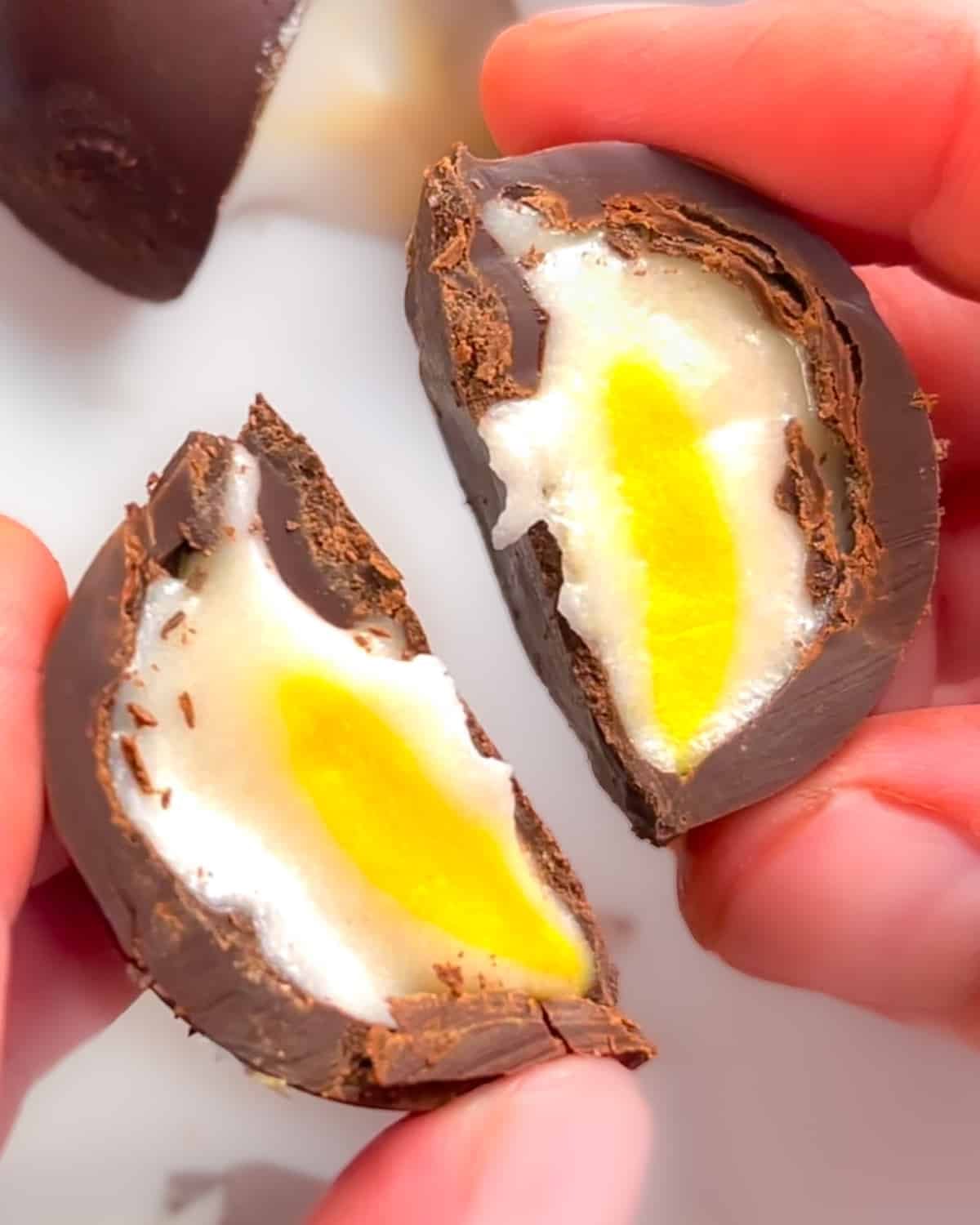 a vegan creme egg cut in half, inside visible