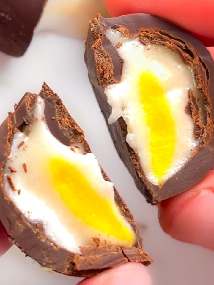 A vegan creme egg cut in half. Inside visible.