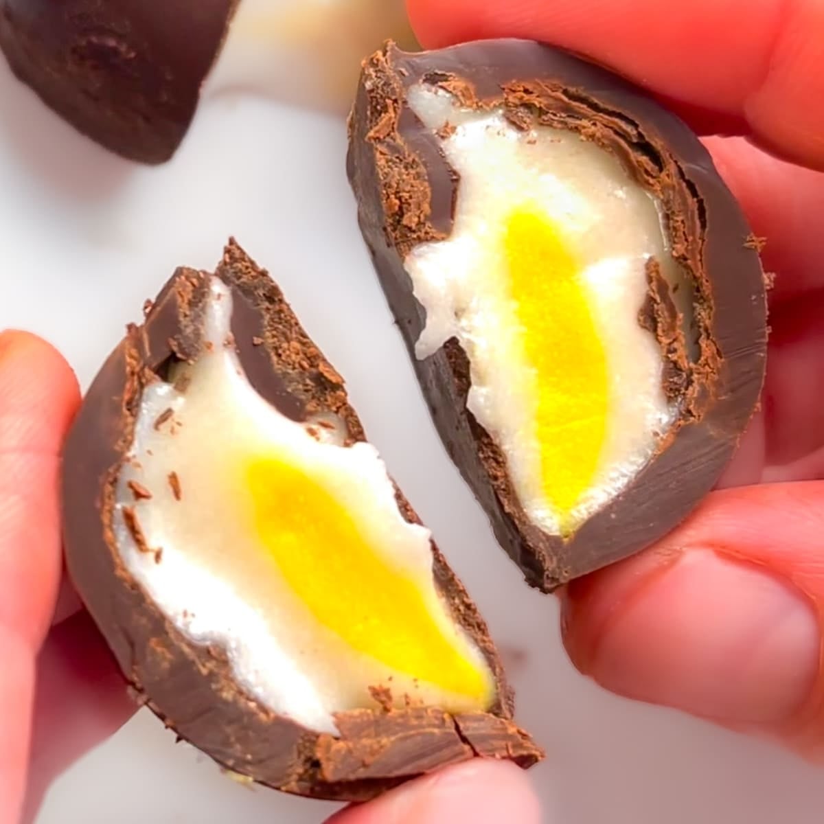 A vegan creme egg cut in half. Inside visible.