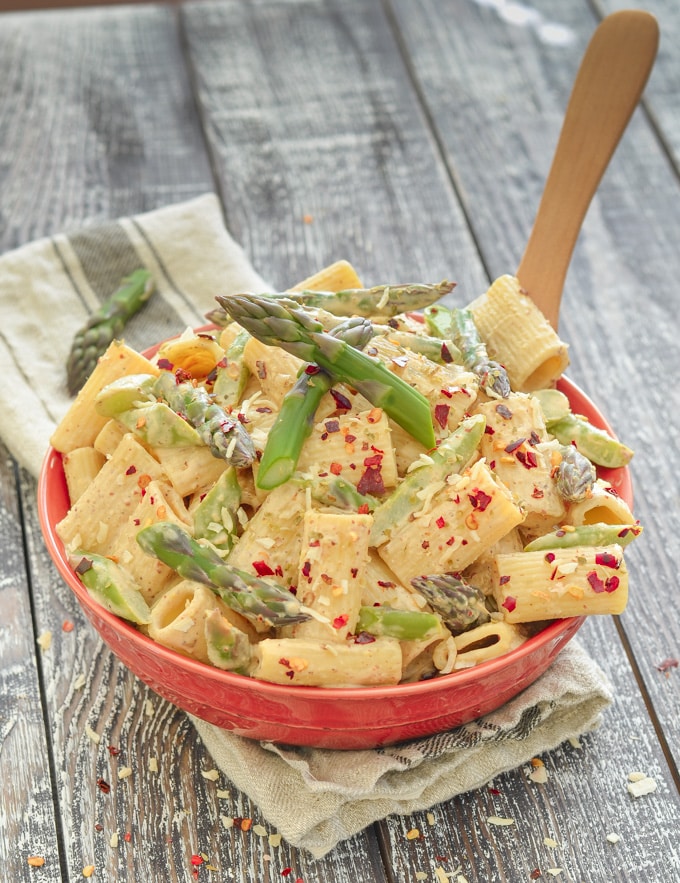 Creamy Asparagus Lemon Pasta Salad in a red bowl on a rustic wood backdrop