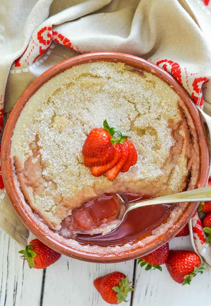 baked strawberry semolina pudding with piece cut out and spoon resting in bowl