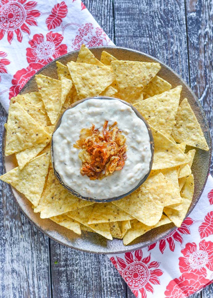 Creamy onion garlic dip topped with caramelized onions and surrounded by tortilla chips