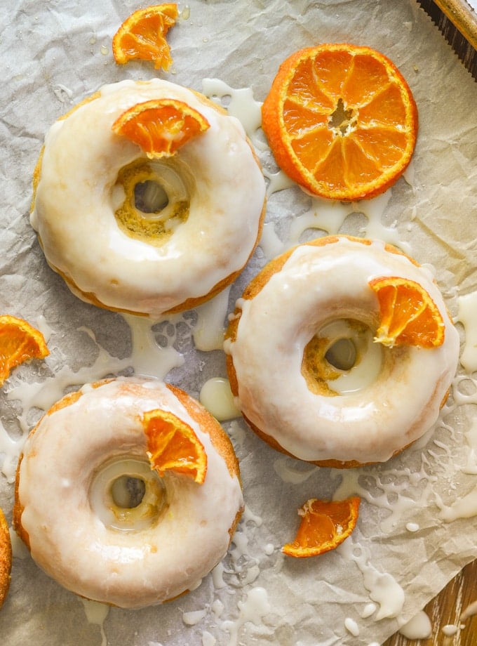 3 frosted, sticky, orange olive oil baked donuts with candied orange pieces
