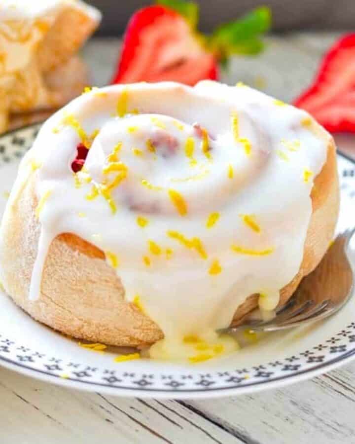 a lemon strawberry sweet roll on a small plate with a fork beside it