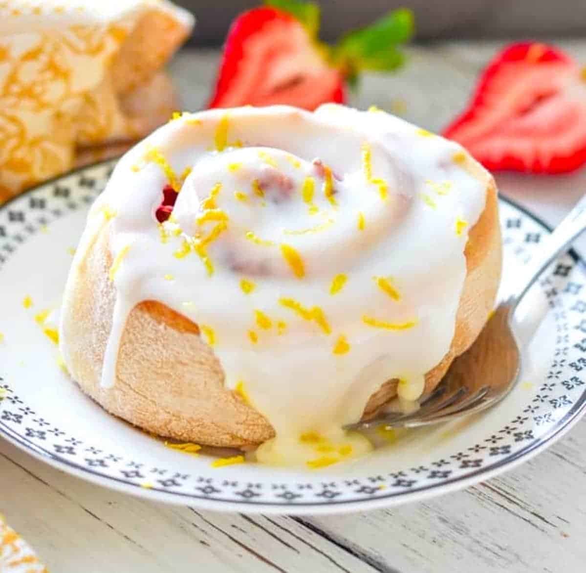 a lemon strawberry sweet roll on a small plate with a fork beside it