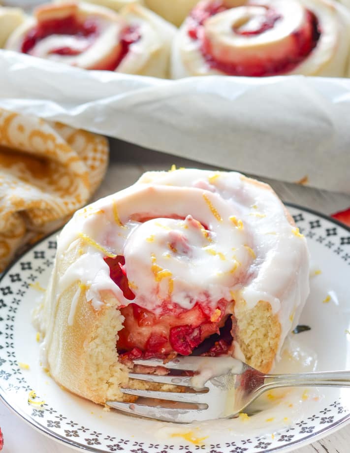 Strawberry Sweet Rolls. Close up of one on a plate with a bite taken out of it. Sticky strawberry filling visible.