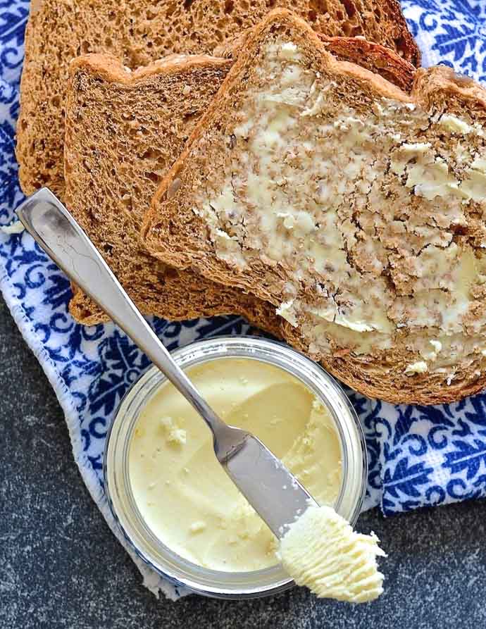 easy vegan butter in jar with knife resting on top with a slice of buttered bread to the side