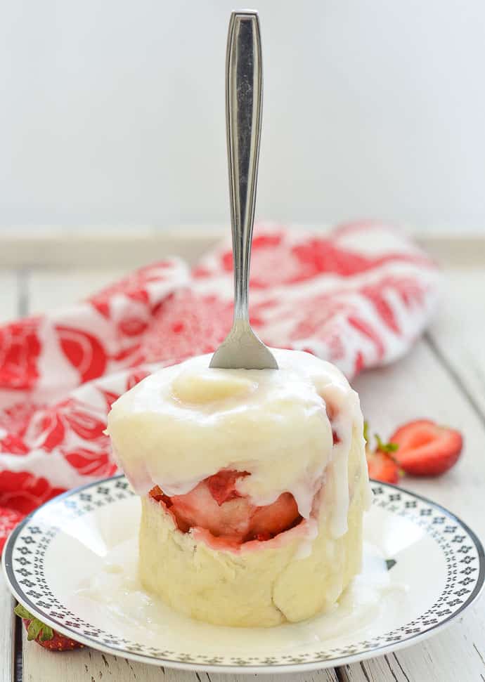 Strawberry Sweet Roll Vegan Mug Cake with drippy frosting on a plate with a fork stuck through it