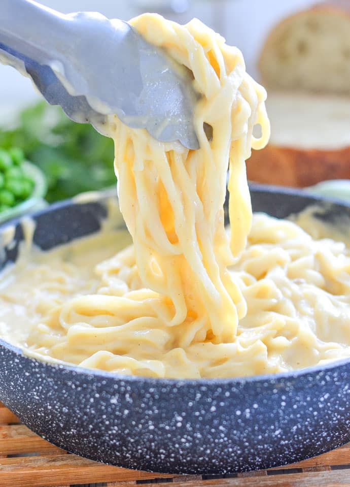 Skinny Fettuccine Cauliflower Alfredo in a pan with tongs lifting some out
