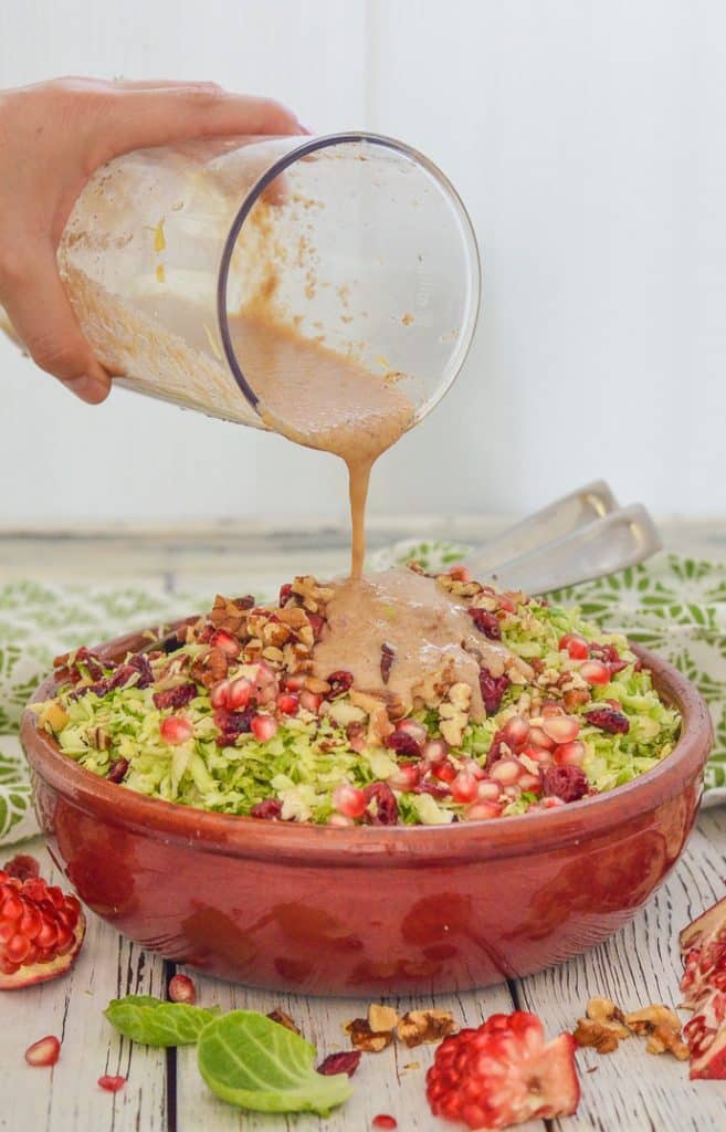 salad dressing being poured over a salad