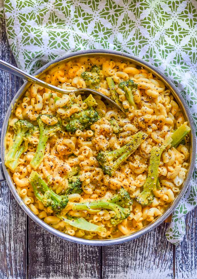 dairy free mac and cheese in a stainless steel pan with broccoli and freshly ground black pepper, taken from above