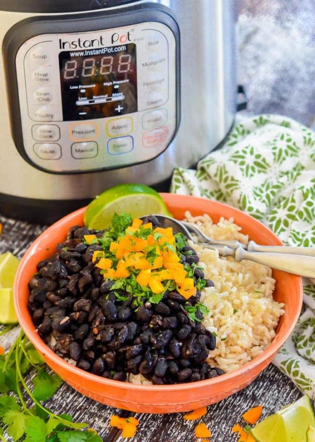 Instant Pot Black Beans in a bowl over rice with the Instant Pot in the background