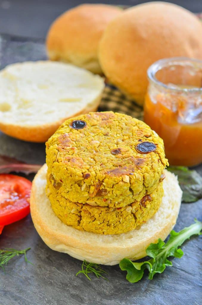 two curried chickpea burgers stacked on an open bun