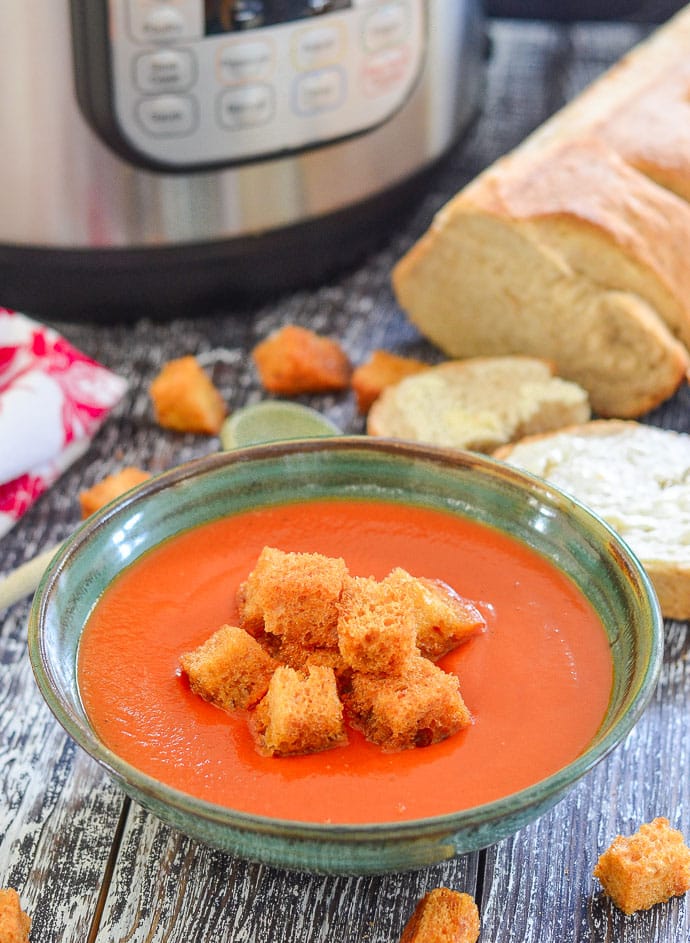 bowl of tomato soup topped with croutons. Instant Pot in the background.