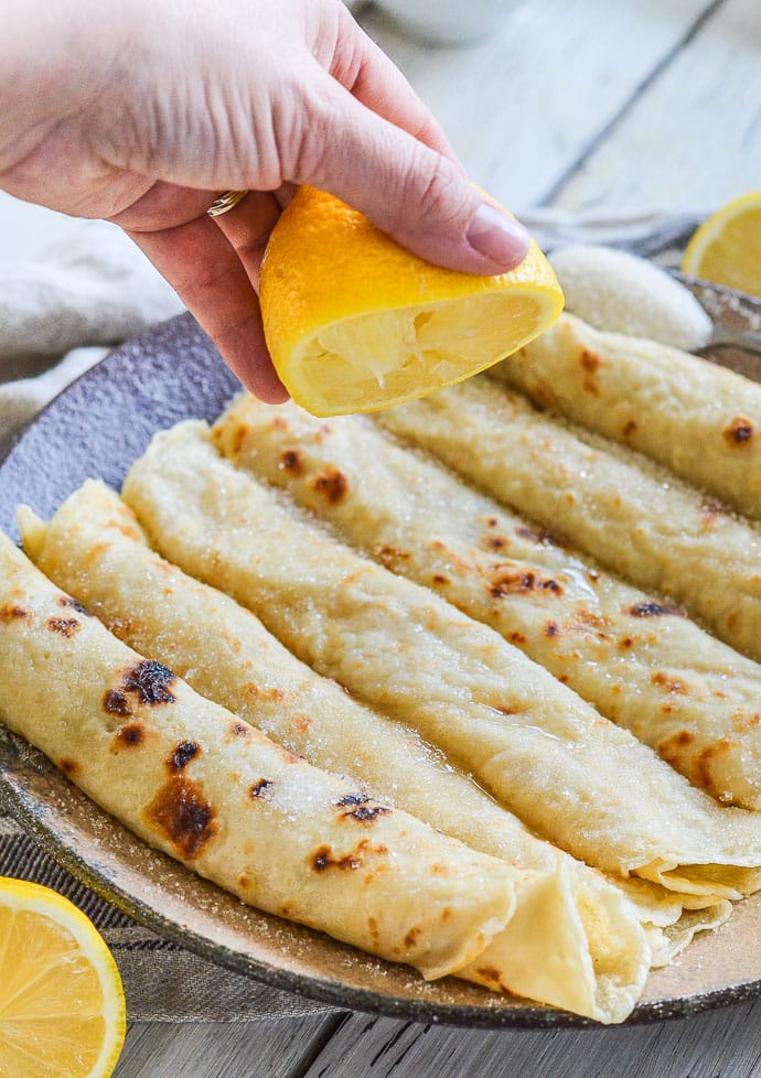 Half a lemon being squeezed on rolled Vegan English Pancakes