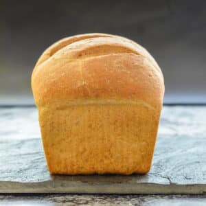 an uncut loaf of crusty bread on a slate board