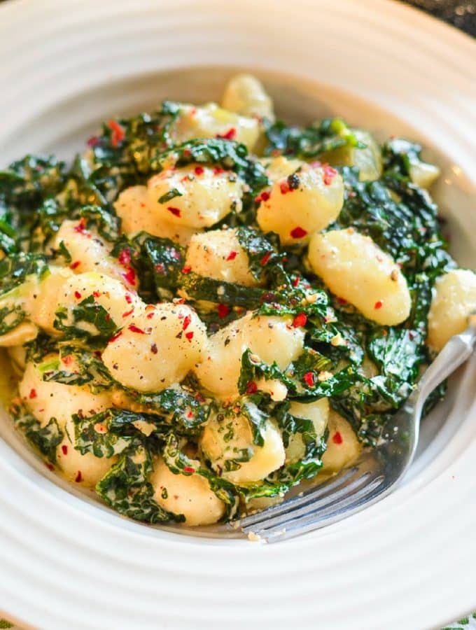 creamy vegan gnocchi with garlic and kale in a bowl