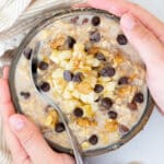 a bowl of chunky monkey overnight oats with hands around it