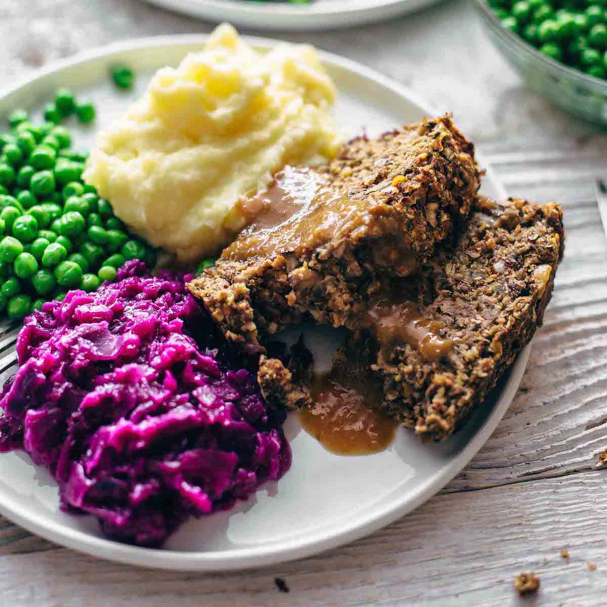 vegan meatloaf, mashed potato, red cabbage and peas on a plate