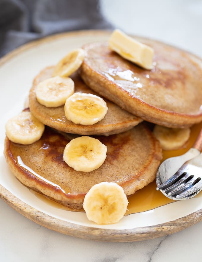 Vegan Banana Pancakes served up on a plate with maple syrup and banana 