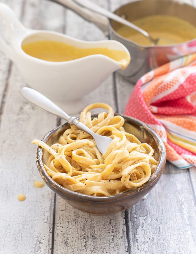 Vegan cheese sauce covered pasta twisted around a fork in a bowl 