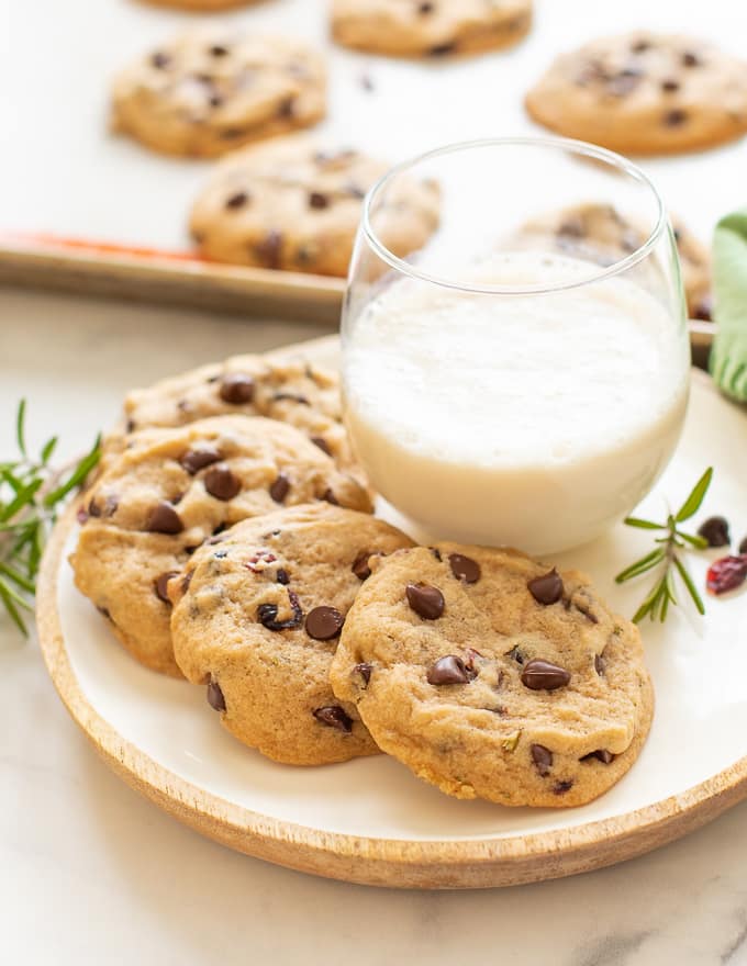 Vegan Chocolate Chip Cookies with Cranberries and Rosemary on a plate with a glass of milk 