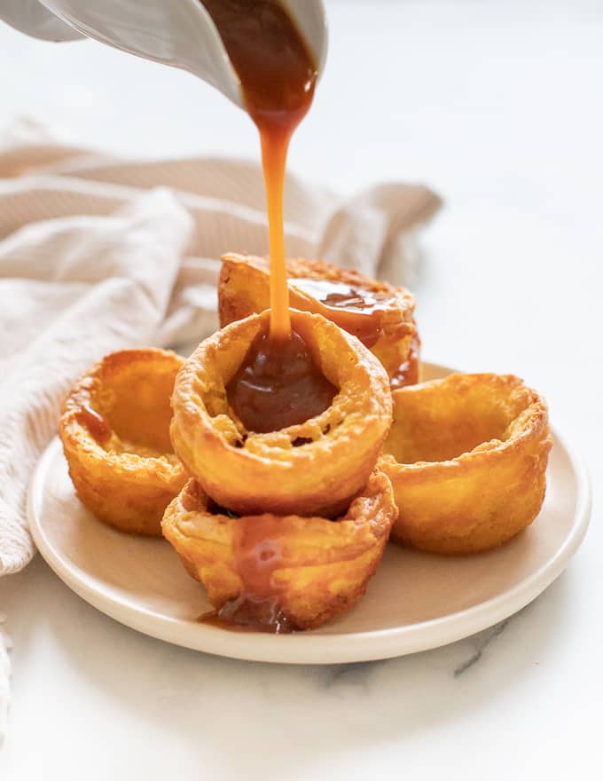 Gravy being poured over a pile of Vegan Yorkshire Puddings. 