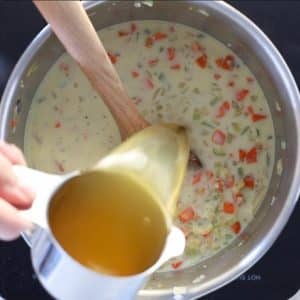 broth pouring into a pan while making vegan potato soup