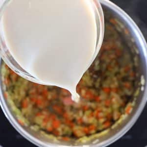 soy milk pouring into pan while making vegan potato soup