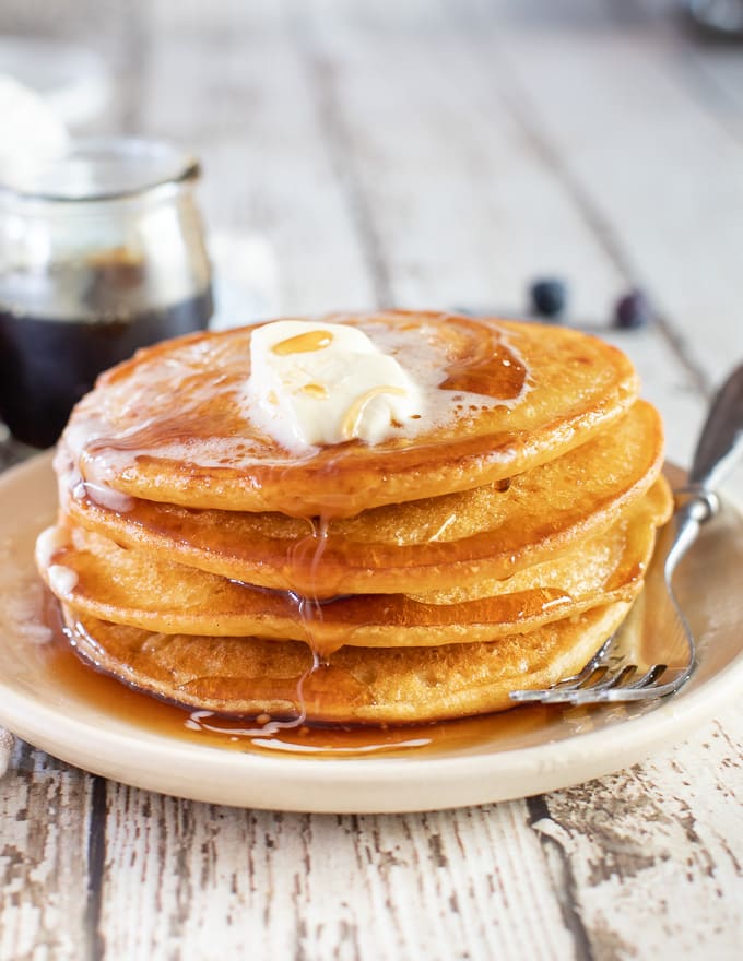 A stack of Vegan Gluten Free Pancakes with lots of vegan butter and maple syrup 