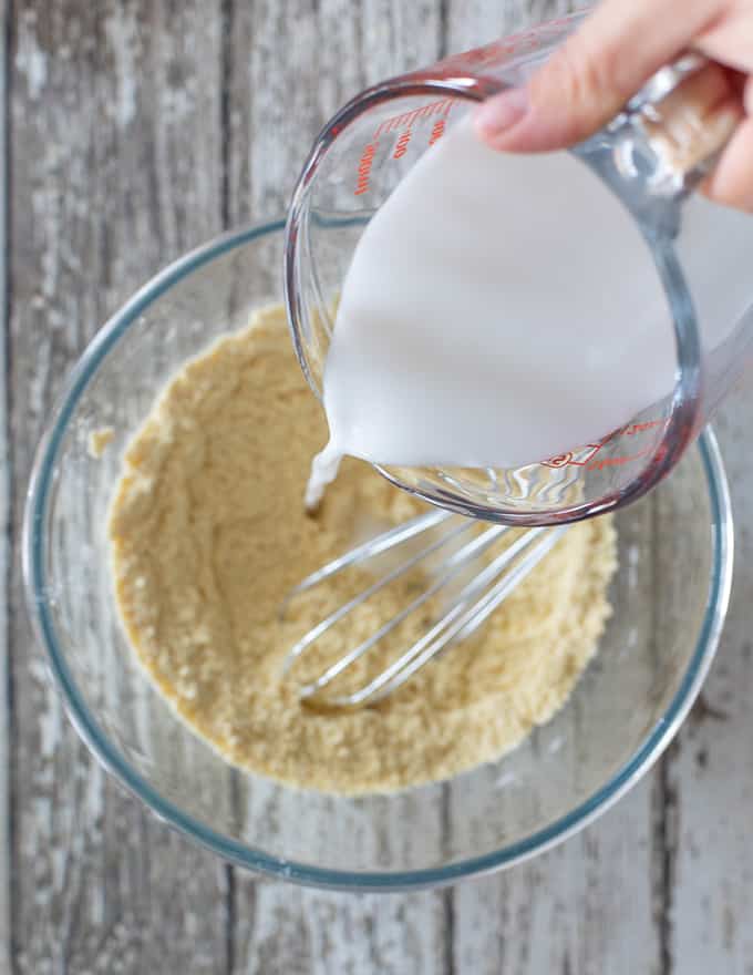 Vegan milk pouring into dry ingredients for Vegan Gluten Free Pancakes