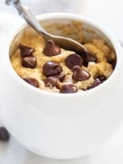 a chocolate chip cookie in a mug with a spoon in it.