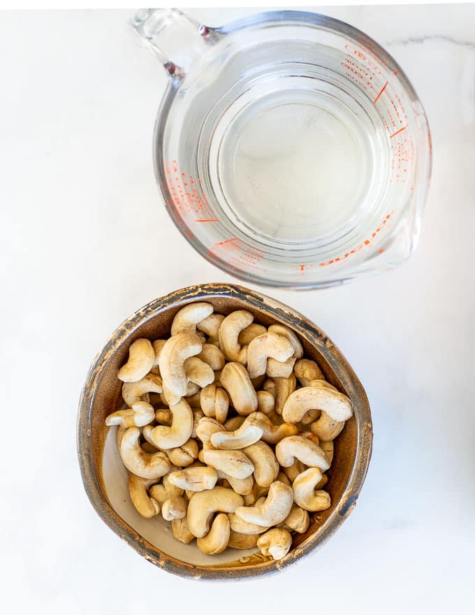 a bowl of cashew nuts and a jug of water