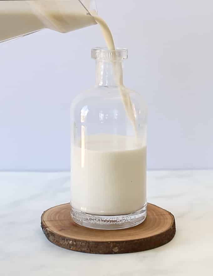 homemade nut milk being poured into a bottle