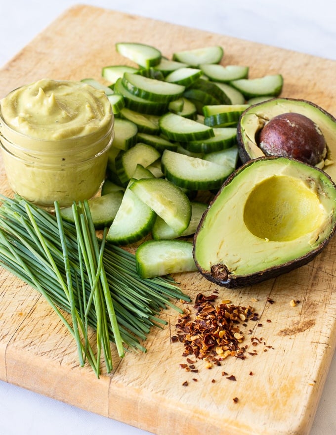 ingredients for Cucumber Avocado Salad on a wooden cutting board 