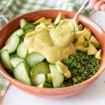 avocado dressing being spooned onto salad