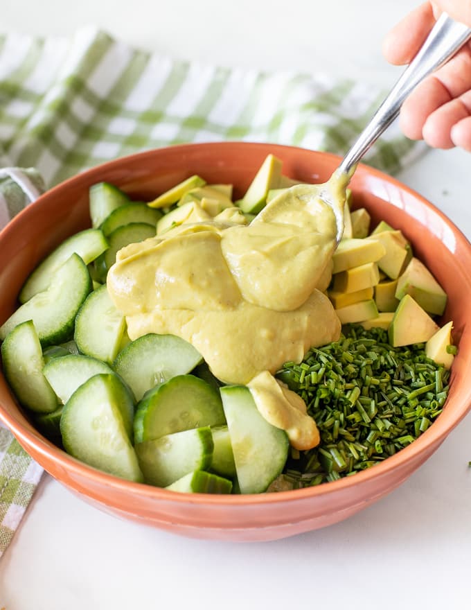 A simple, lemony, avocado-creamy, crunchy and fresh Cucumber Avocado Salad that's really quick and easy to make! Cucumber Avocado Salad with avocado dressing being dolloped on