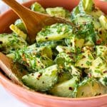 Cucumber Avocado Salad with fresh dill in a bowl with salad servers