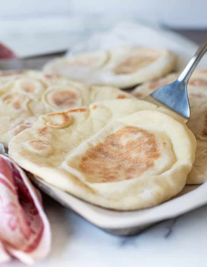 a flatbread being removed from a tray with a spatula