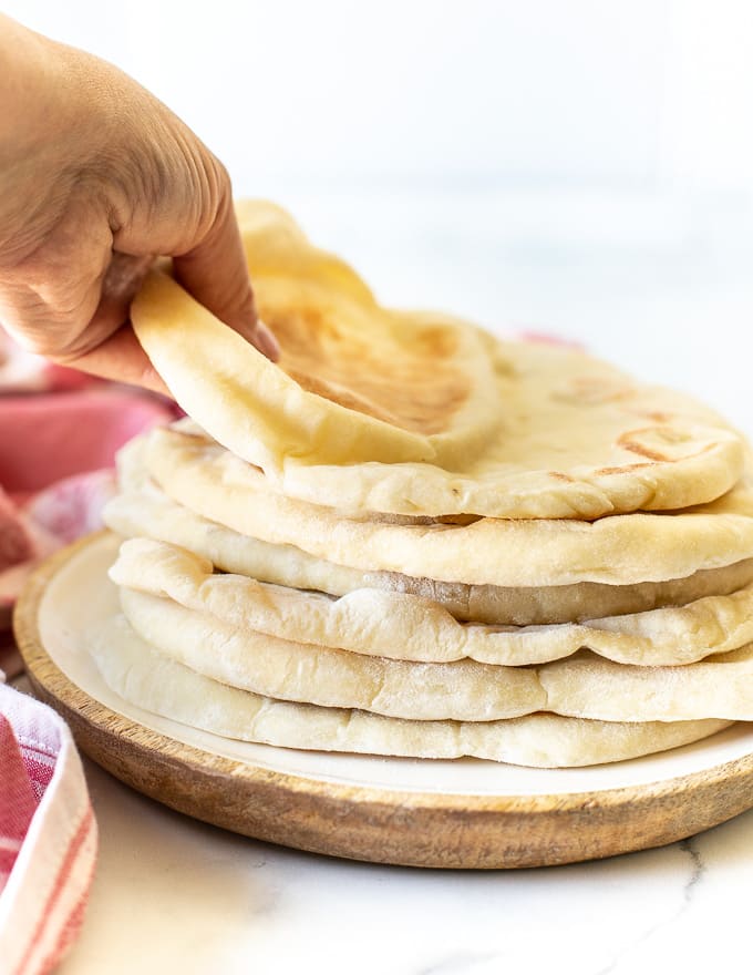 someone taking a flatbread from the top of a pile 