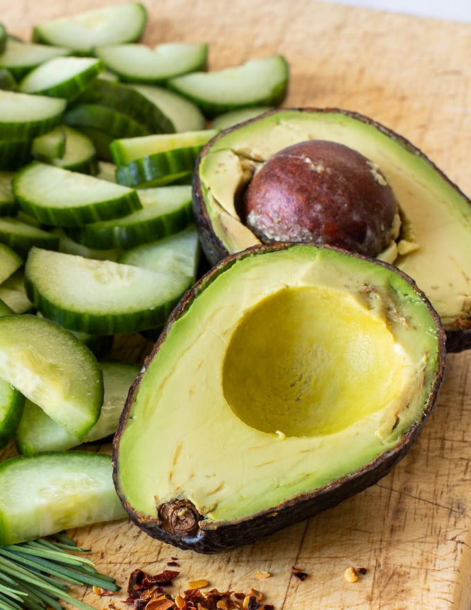 avocado cut in half on wooden board