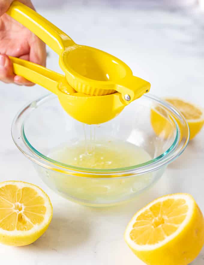 half a lemon being juiced over a bowl 