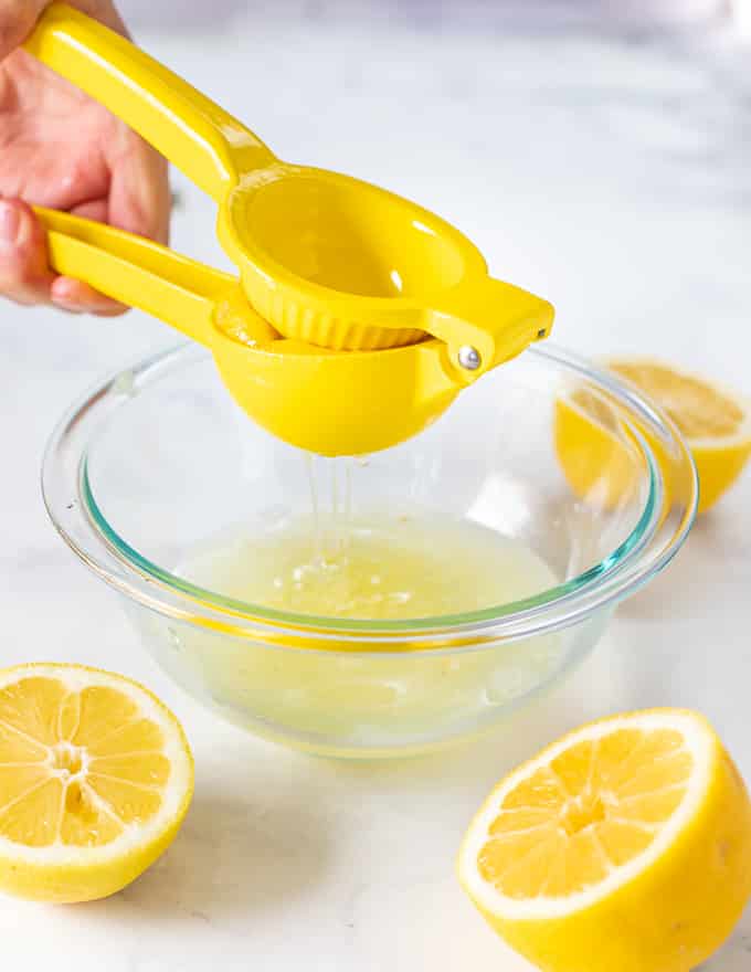 half a lemon being juiced over a bowl