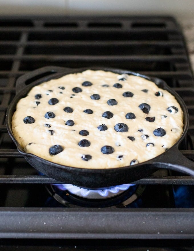 giant blueberry vegan pancake cooking in a pan on the stove top