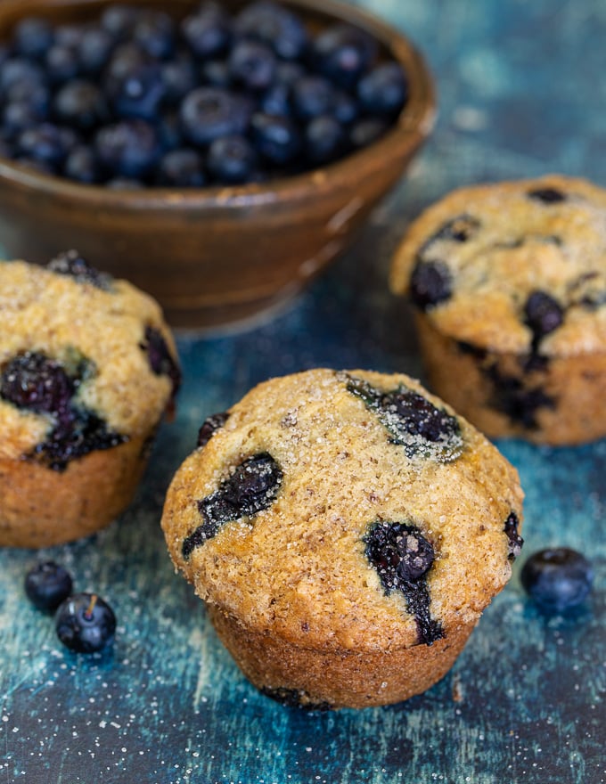 close up shot of vegan blueberry muffins and a bowl of fresh blueberries