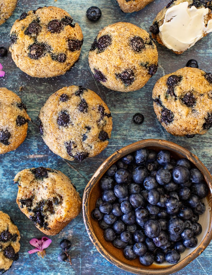 overhead shot of vegan blueberry muffins and a bowl of fresh blueberries