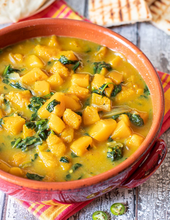 butternut squash curry in a red terracotta serving dish