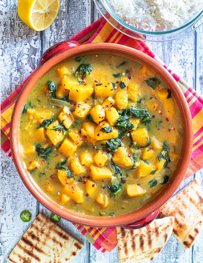 overhead photo of a red terracotta serving dish with butternut squash curry in it